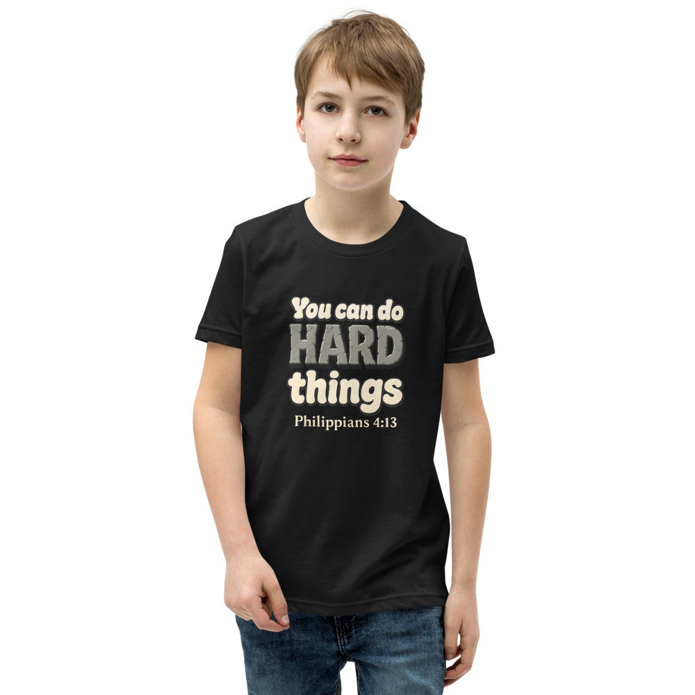 Black youth t-shirt printed with “You can do HARD things” in cracked stone letters and Philippians 4:13