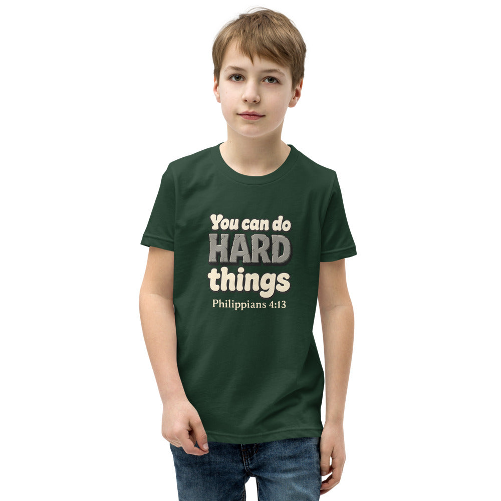 Forest youth t-shirt printed with “You can do HARD things” in cracked stone letters and Philippians 4:13